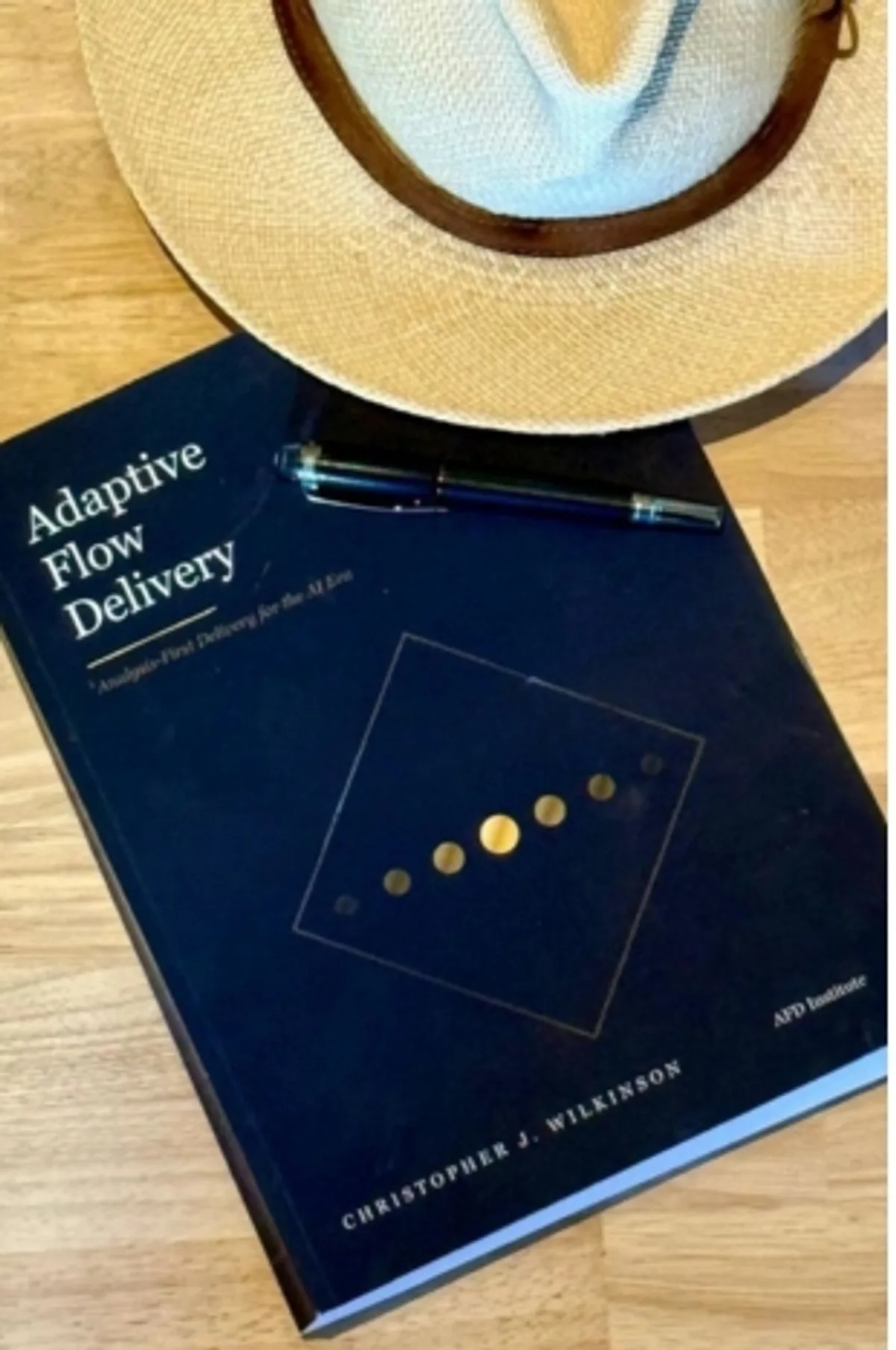 Het boek Adaptive Flow Delivery van Christopher J. Wilkinson, met hoed en pen